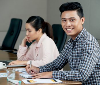 Portrait of happy young Asian businessman attending meeting